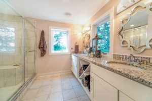 White vanity cabinets opposite glass shower