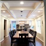 Looking down wood dining room table into kitchen with white cabinets