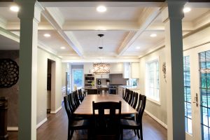 Looking down wood dining room table into kitchen with white cabinets