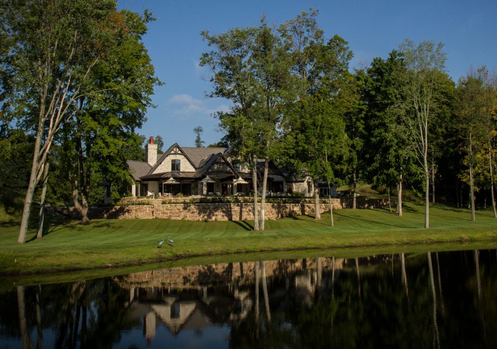 Large stone home set in the trees overlooking a pond