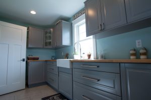 Grey laundry room cabinets with farmhouse sink