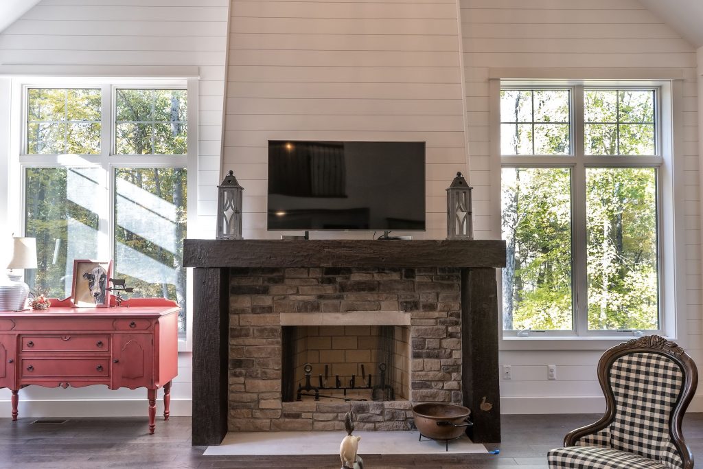 Stone fireplace with timber surround and wood planks on walls