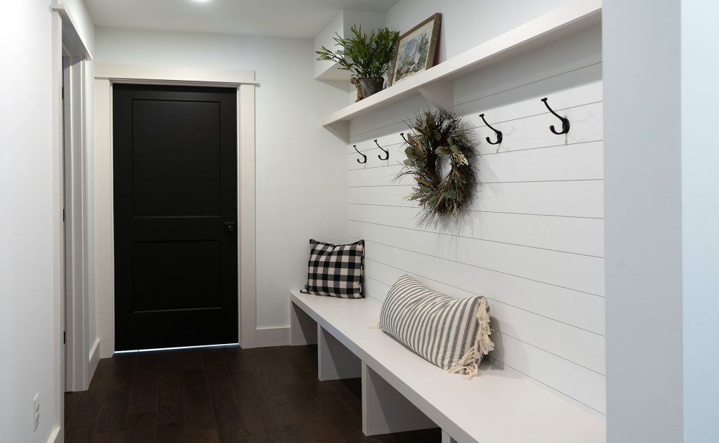 White bench with white wall planking and coat hooks