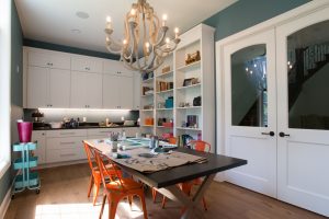 Dark wood craft table in room with white cabinets