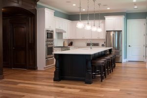 Large wood island with white marble top in kitchen with white cabinets