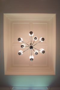 Chandelier hanging from wood trimmed tray ceiling