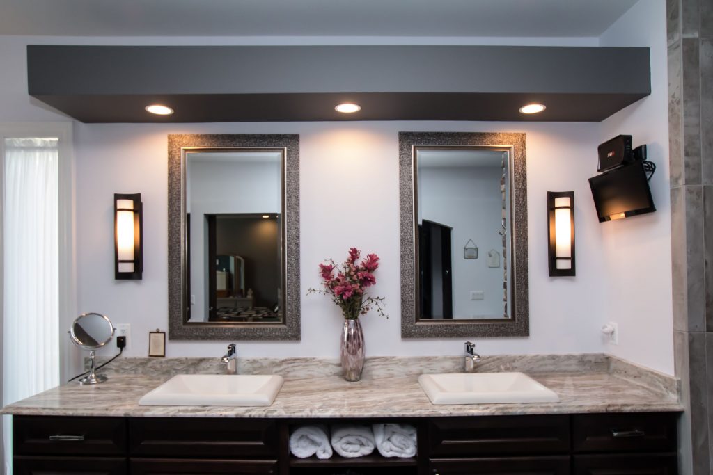Granite counter with two sinks, wall mirrors and lighted soffit