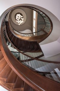 Looking up from the lower level through the center of a custom curved wood stairway
