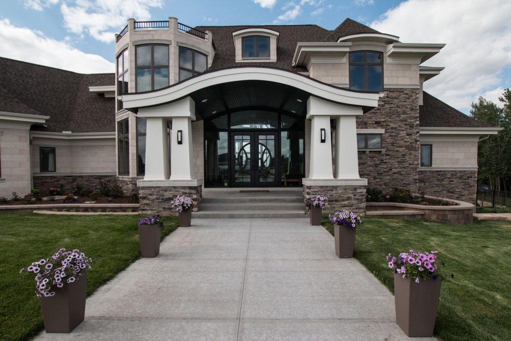 Entry of home with curved porch roof and large tapered columns