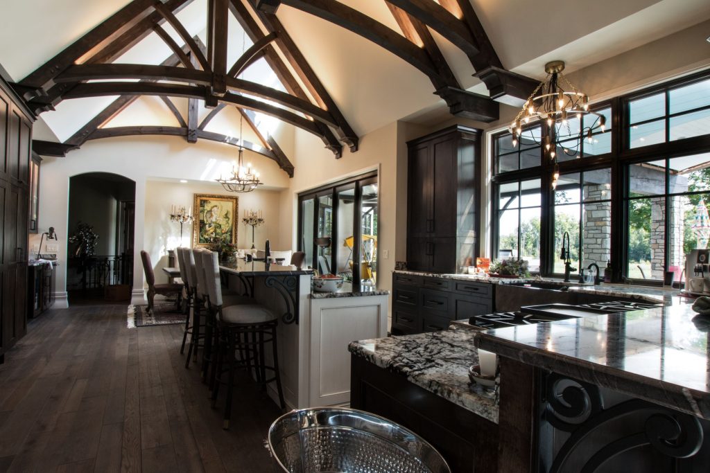 Dark wood kitchen cabinets with granite counters accent the timber trusses at the ceiling