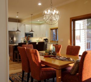 Upholstered chairs set around a dining room table with the kitchen beyond